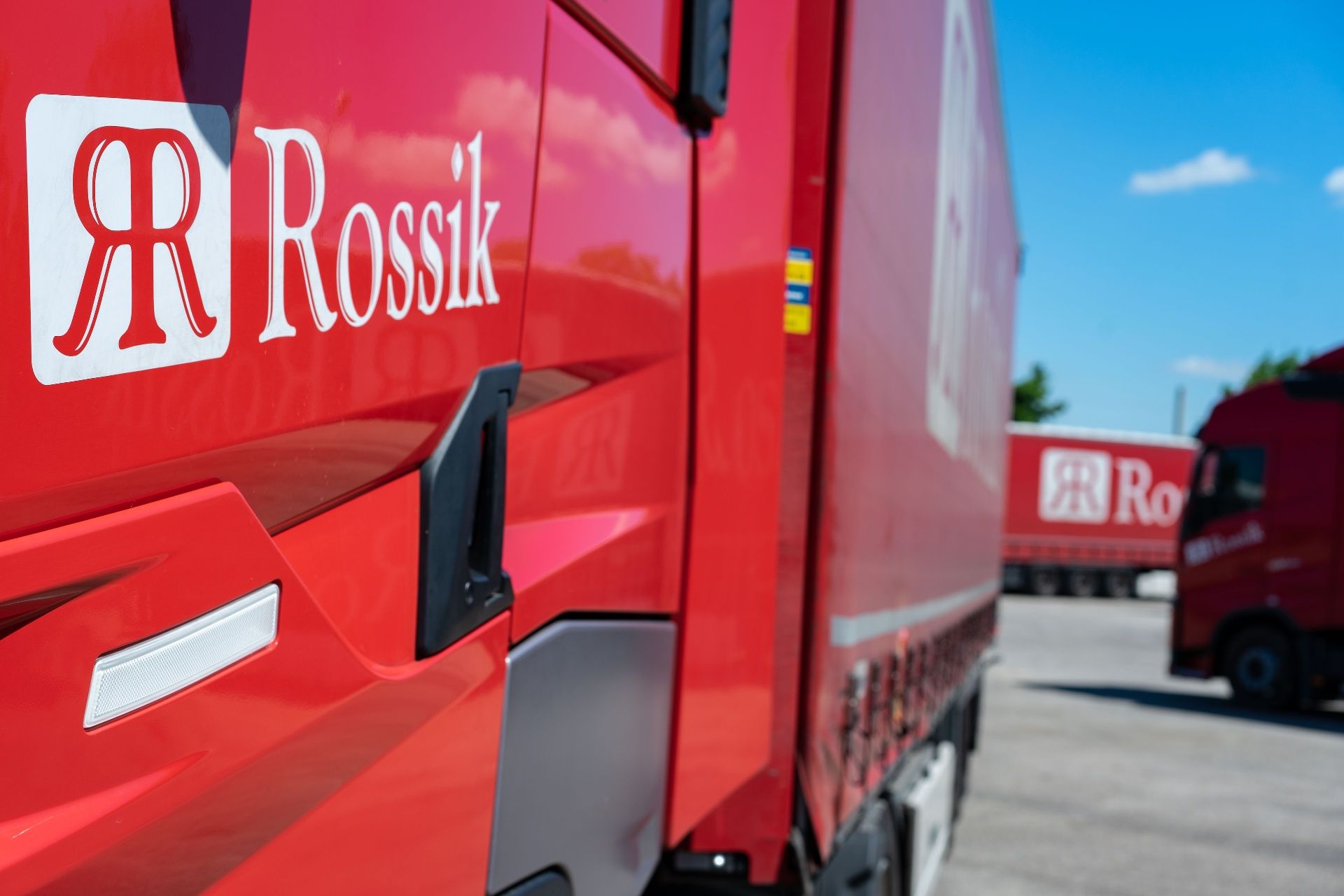Rossik-Logo auf der Fahrerkabine eines roten LKW, im Hintergrund weitere Rossik-Fahrzeuge