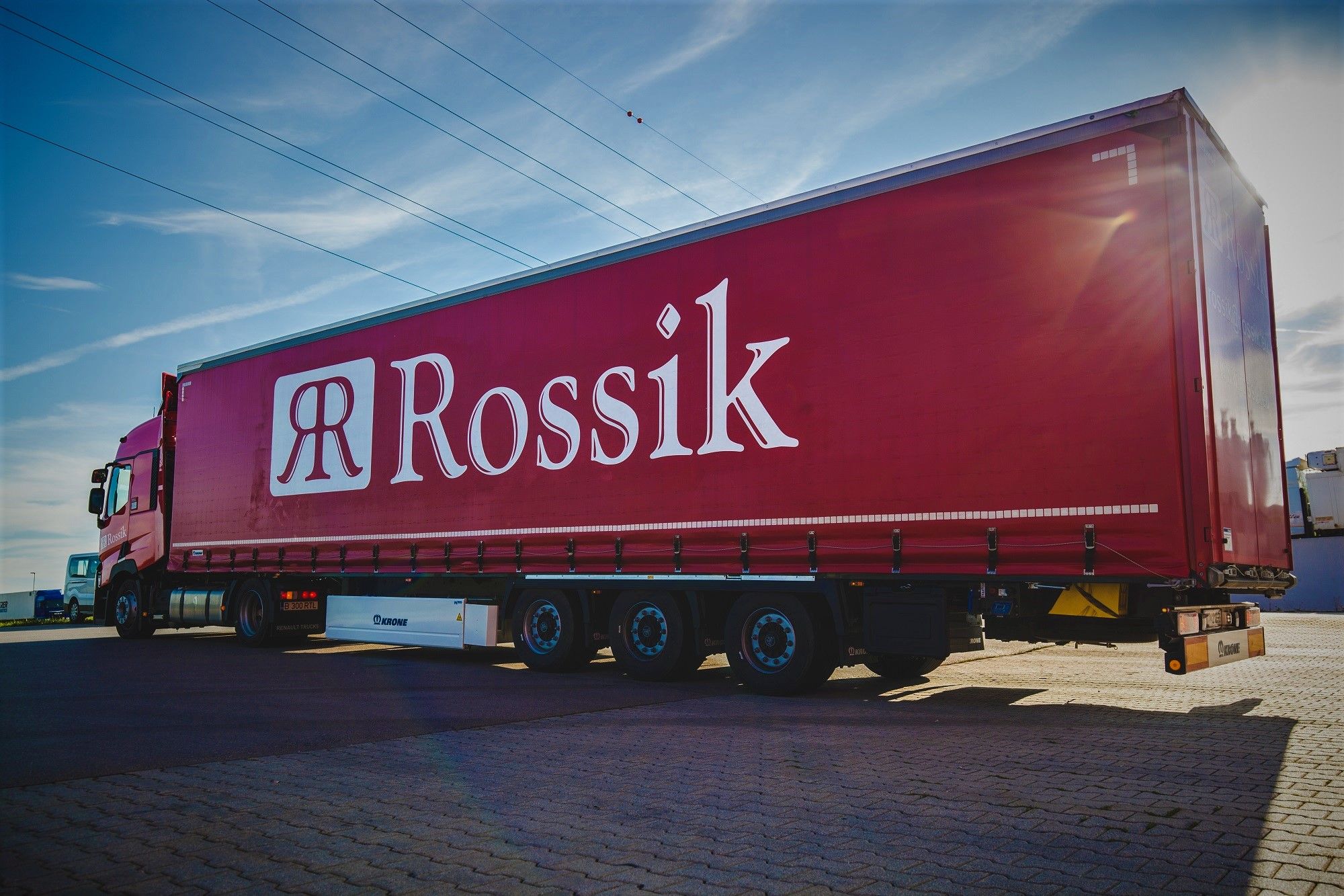 Sattelzug mit rotem Rossik-Planenauflieger auf dem Betriebsgelände